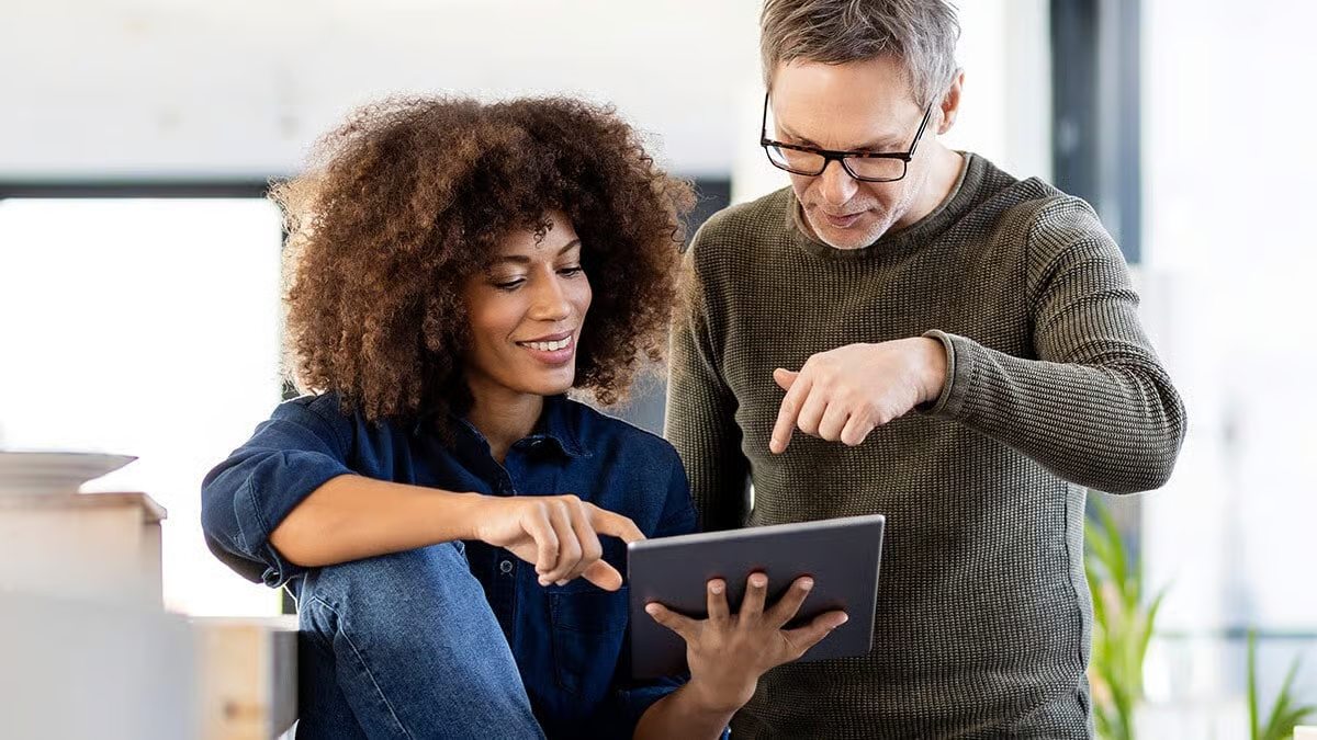 Two colleagues reviewing business data together on a tablet